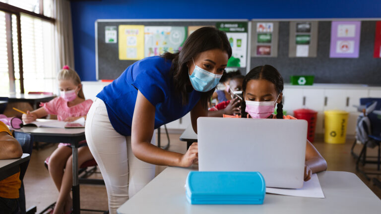 Teacher assists student with electronic learning assignment